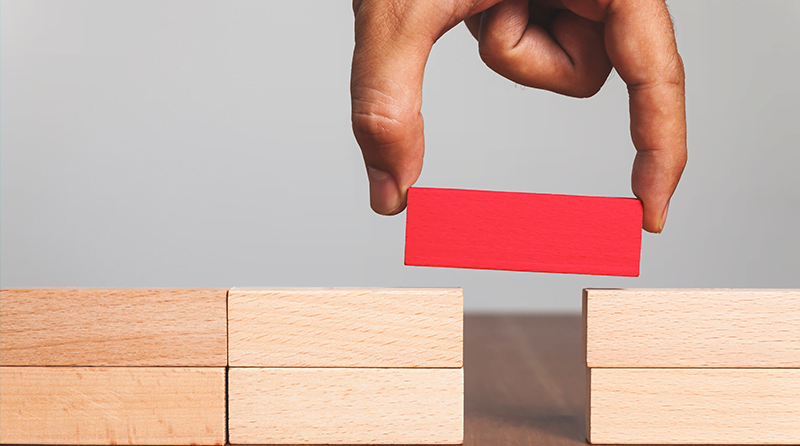 Stacks of blocks with an open space and a hand placing a red block representing FDX API Security