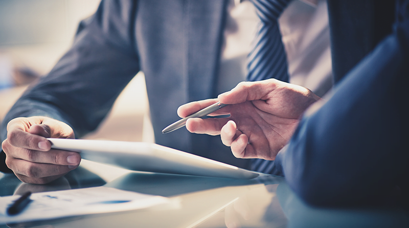 Business men looking at a paper and holding a pen representing API Security KuppingerCole